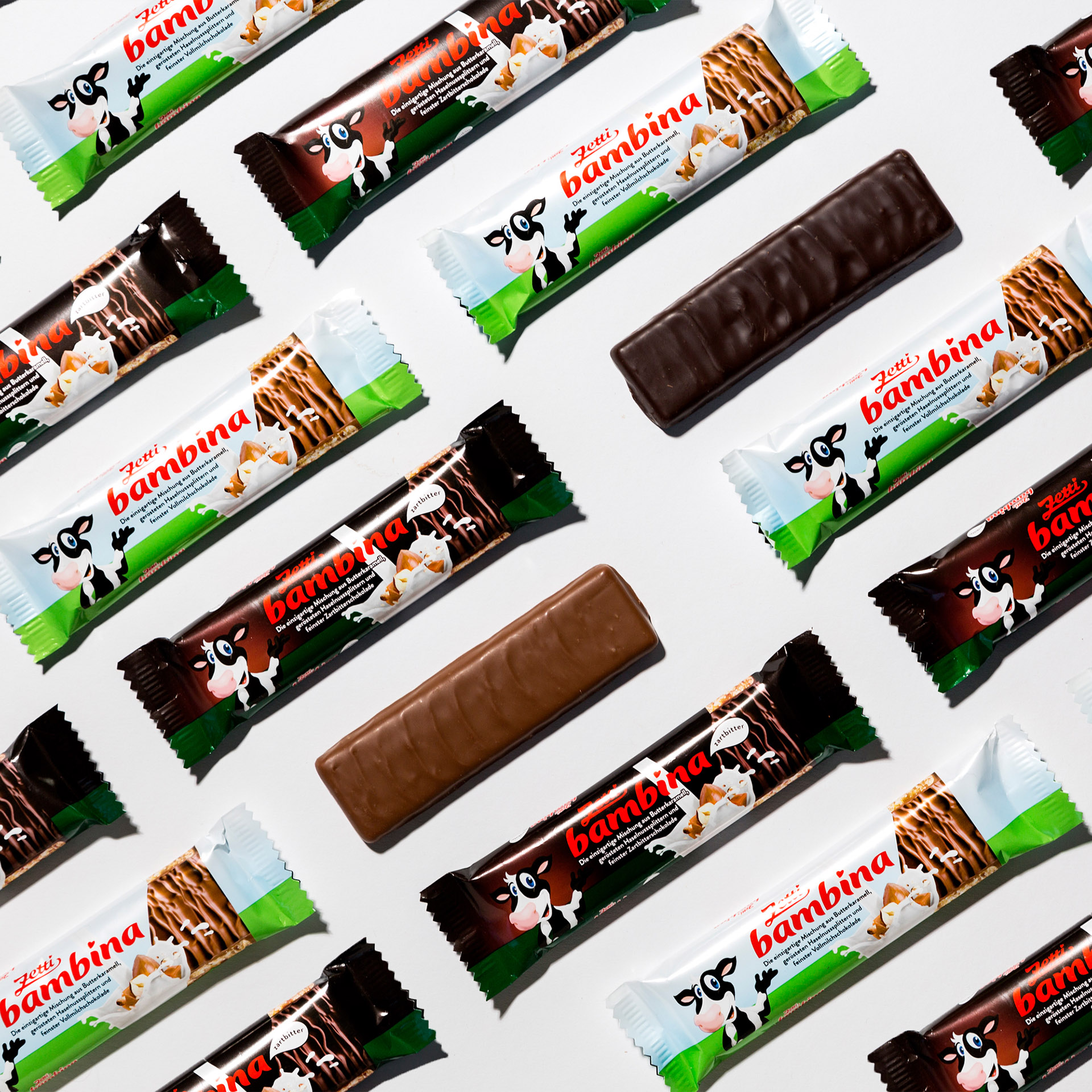 Zetti Bambina Riegel Vollmilch Eine Abbildung aneinander gereihter Riegel in den Sorten Zetti Bambina Vollmilch und Zartbitter